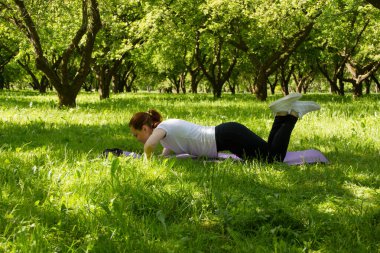 Bir yaz sabahı parkta koştuktan sonra termo bardaktan çay içen genç bir kadın.