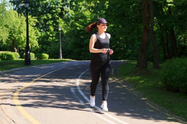 Bir yaz sabahı parkta koşan bir kadın.