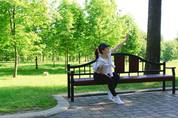 一个夏日的早晨 年轻的女人在公园里慢跑之后 坐在长椅上 — 图库照片