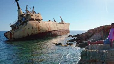 Genç bir kadın, açık mavi bir günde, açık mavi gökyüzünün altında Paphos yakınlarındaki popüler bir turizm merkezi olan ikonik Edro III 'ün enkazına hayran kaldı.