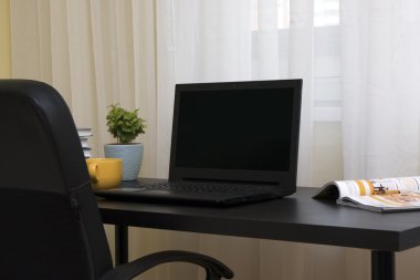 İşyeri: dizüstü bilgisayar, kitap ve çay siyah masa üzerinde