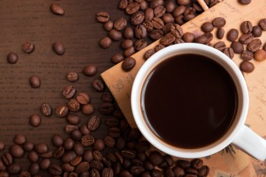 Fincan kahve ve koyu kahverengi masada kahve çekirdekleri
