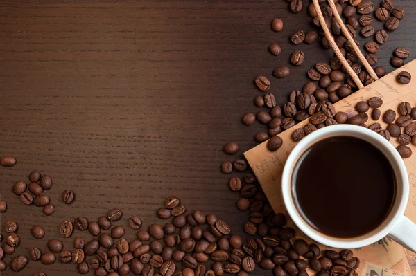 Kopp kaffe och kaffebönor på mörka bruna bord — Stockfoto