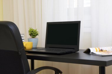 İşyeri: dizüstü bilgisayar, kitap ve çay siyah masa üzerinde