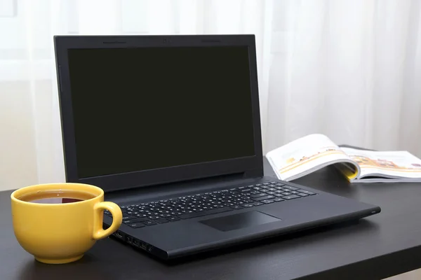 İşyeri: dizüstü bilgisayar, kitap ve çay siyah masa üzerinde