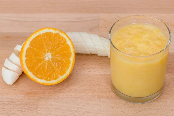 Помаранчевий і банановий смузі в склі на помаранчевому фоні — стокове фото