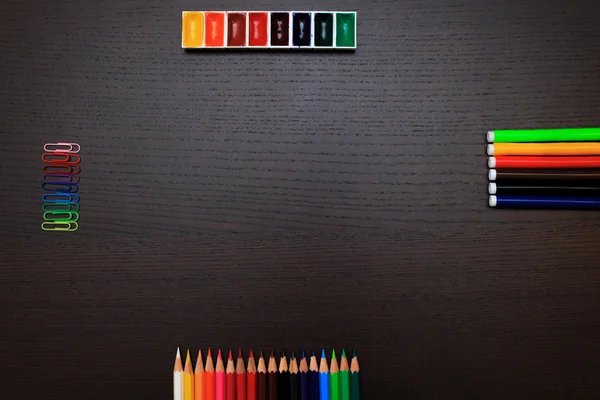 Színes ceruzák, festékek, klipek és markerek a sötét háttér előtt — Stock Fotó