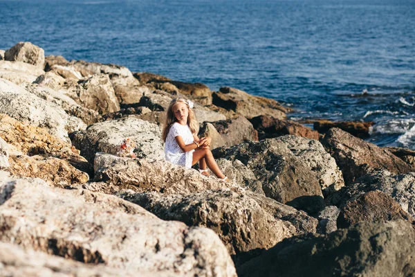 Hermosa chica de pie en la costa rocosa — Foto de Stock