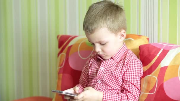 Мальчик играет в игру на смартфоне — стоковое видео