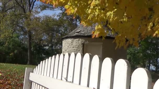 Autumn landscape with falling leaves, picket fences and a stone shack — Stock Video