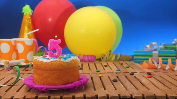 誕生日のケーキの背景色とりどりの風船、ギフト、プラスチックのコップと青い壁が背景とお菓子素朴な木製のテーブルの上のろうそく — ストック写真