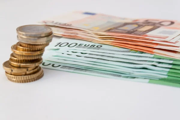 Moneda en euros en el fondo de los billetes — Foto de Stock