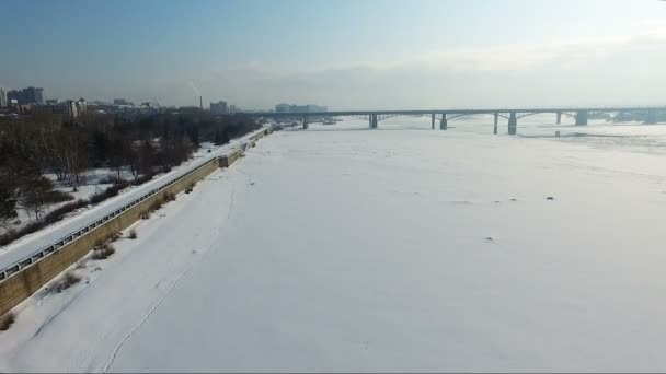 Літати над замерзлою річкою взимку. Міст через річку. набережна — стокове відео