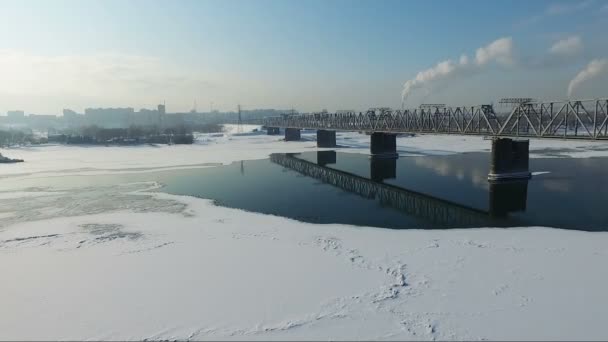 Літати над замерзлою річкою взимку. Міст через річку — стокове відео