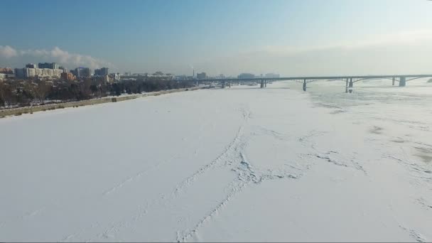 Flying over the frozen river in winter. Bridge over river. embankment — Stock Video