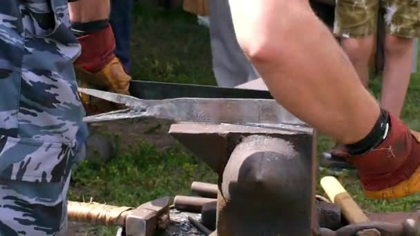 Un herrero modela una barra de hierro con martillo después de tomarla de la fragua de fuego . — Vídeos de Stock