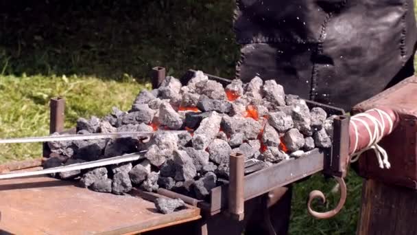 Un forgeron modèle une barre de fer avec un marteau après l'avoir prise de la forge de feu . — Video