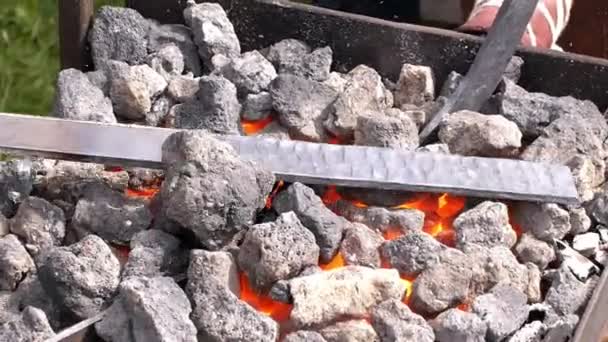 Un herrero modela una barra de hierro con martillo después de tomarla de la fragua de fuego . — Vídeo de stock