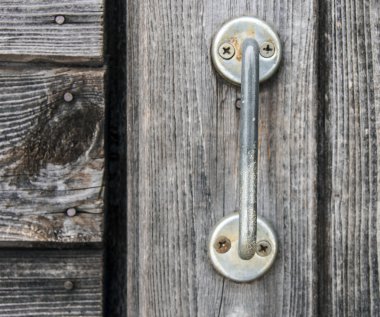 Eski gri ahşap kapı üzerindeki metal kolu