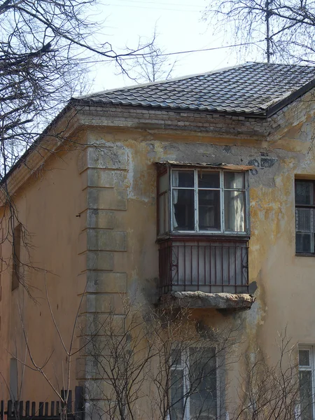 Old dilapidated yellow two-story building with tumbledown balcon — Stock Photo, Image