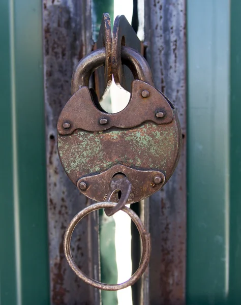 Velho cadeado de metal enferrujado com chave em portões de metal verde close-up — Fotografia de Stock