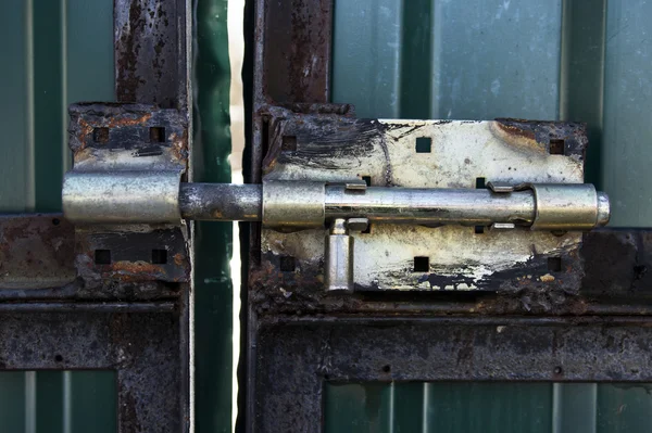 Vieux loquet en laiton métallique rouillé grossièrement velu aux portes métalliques vertes — Photo