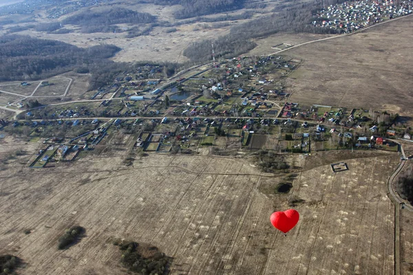 kırmızı kalp şeklinde kırmızı balon arazi üzerinde gezinir - 