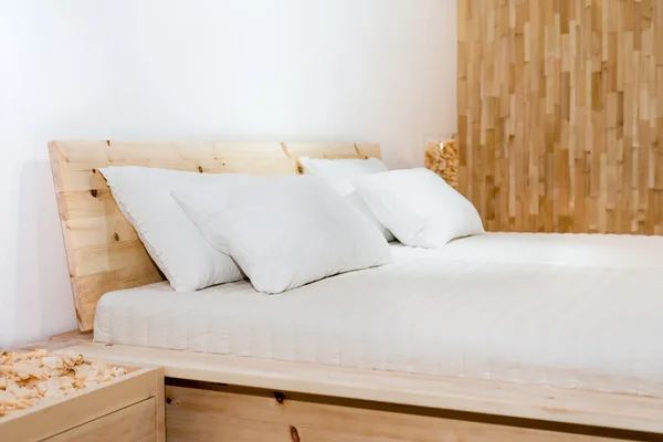 Beyaz yastıklı ahşap yatak.