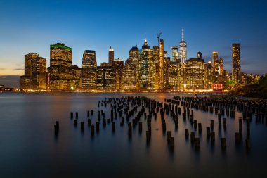Doğu nehrinin ahşap kütükleri ve aşağı Manhattan silueti mavi saatte. New York 'un uzun pozlu fotoğrafı.