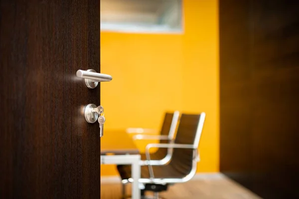 Anahtarlar ofisin açık kapısında. Portakal tasarımında mobilyalı çalışma yeri.