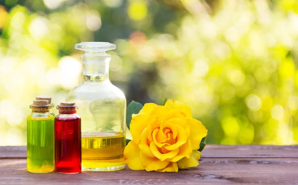 Natural rose oil and flower elixirs body. Spa treatment and massage. Fragrant yellow rose. Vintage glass bottles. Aromatherapy and Alternative Medicine. Green blur. Copy space.