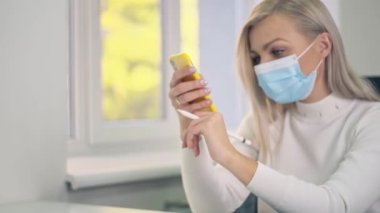 Coronavirus önleme için koruyucu maske takan kadın. Elinde Stylus olan bir iş kızı Covid 19 için karantinada cep telefonu kullanıyor..