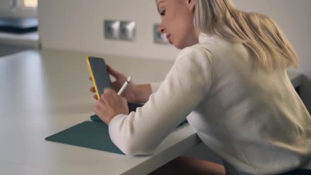 在Covid 19检疫期间 使用手机和数码平板电脑在网上授课的年轻女性的回顾 在家庭办公室用数字笔为工作做电话和数字平板电脑的女孩 — 图库视频影像