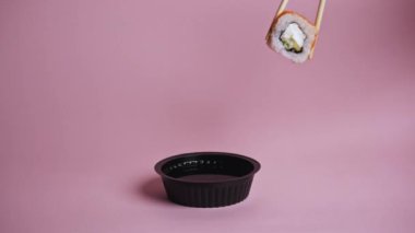 Ahşap suşi çubukları çeşitli ruloları renkli bir arka planda bir fincan soya sosuyla tutar. İnternetten yemek sipariş et. Japon mutfağı, yemek teslimatı. 
