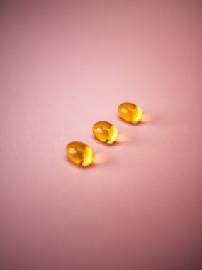 Seçici odaklı kapsül balığı yağı pembe arka planda izole edilir. Sağlık hizmeti kavramı