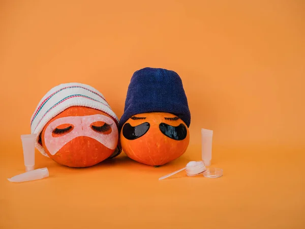 Två Pumpa Med Ögonlappar Ansiktsmask Och Handduk Orange Bakgrund Kopiera — Stockfoto