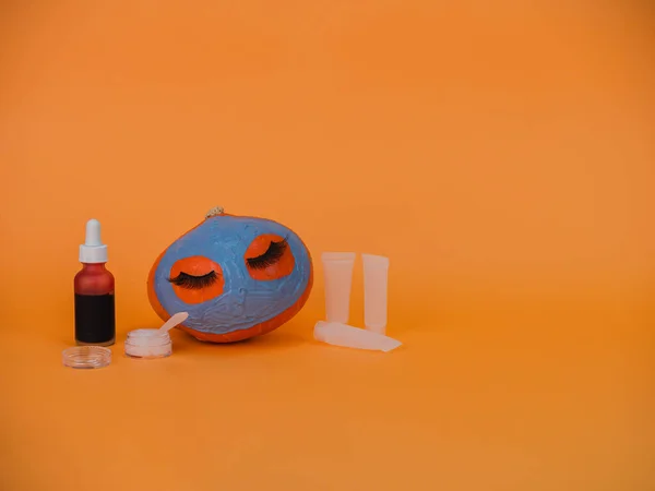 Dynia Maską Pomarańczowym Tle Przestrzeń Kopiowania Akcesoria Pielęgnacji Skóry Halloween — Zdjęcie stockowe
