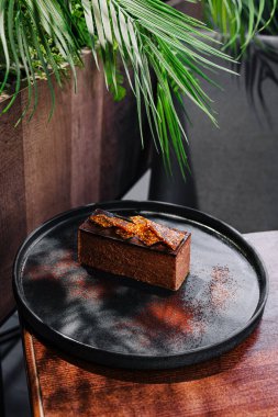 Çok güzel işlenmiş bir çikolatalı tatlı yemyeşil bir tabakta oturur.