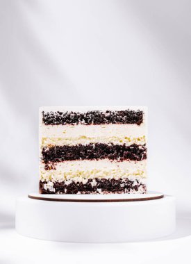 Güzel katmanlı bir pasta zengin çikolata ve kremalı beyaz katmanlar sergiler. Basit beyaz bir standa yerleştirilmiş, iyi ışıklandırılmış ve karmaşık tasarımın altını çiziyor. Özel bir kutlama için mükemmel..