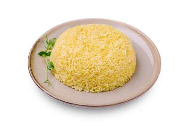 Taze otlarla süslenmiş bej bir tabakta tüylü sarı pirinç yığını sunulur. Yemek iştah açıcı görünüyor ve her yemek için mükemmel..