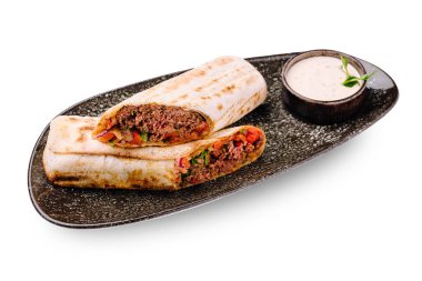 Sığır eti ve taze sebzelerle dolu iki lezzetli paket yanında küçük bir kase kremalı sosla birlikte koyu bir tabakta dinleniyor. Bu yemek öğle ya da akşam yemeği için mükemmel..