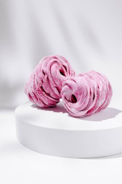 İki güzel pembe pasta pürüzsüz beyaz bir kaide üzerinde zarif bir şekilde sergilenir. Karmaşık girdap tasarımı ve parıldayan şeker kaplaması tatlı aşıkları için davetkar bir görünüm yaratır..