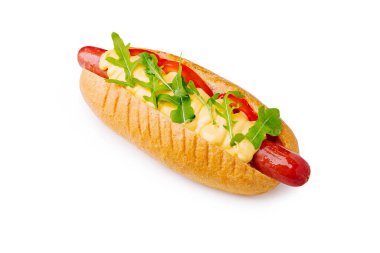 Bir sosisli sandviç üzerine hardal, doğranmış domates ve taze roka konur. Sunum basit ve davetkar, içeriğinin canlı renklerini gösteriyor..