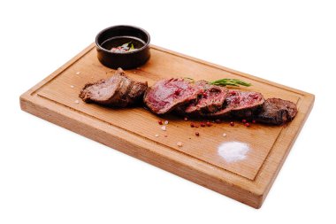 Sulu biftek dilimlenir ve ahşap bir tahtada sunulur. Yanında küçük bir kase sos, tuz taneleri ve renkli biber taneleriyle birlikte tabağa tat ve doku ekler..