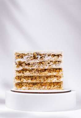 Çok güzel hazırlanmış çok katmanlı bir pasta beyaz bir kaidede oturur. Katmanlar çeşitli dokuları gözler önüne seriyor. Lezzetli ve davetkar bir tatlıyı işaret ediyor. Kutlamalar ya da toplantılar için mükemmel..