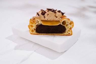 Lezzetli bir tatlı sergileniyor, içinde bol çikolatalı ve kremalı katmanlar yer alıyor. Çikolata parçacıkları zarafet katar..