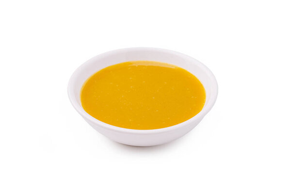 A small white bowl holds a smooth, golden sauce that glimmers under the light. The vibrant color suggests rich flavor, ideal for dipping or drizzling on dishes.