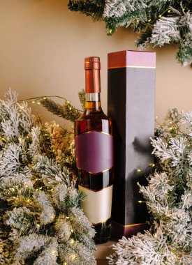 Çok güzel sunulmuş bir viski şişesi buzlu yeşillikler ve yumuşak ışıkların arasında duruyor. Sıcak ve davetkar bir atmosfer yaratıyor. Tatil kutlamaları için mükemmel..