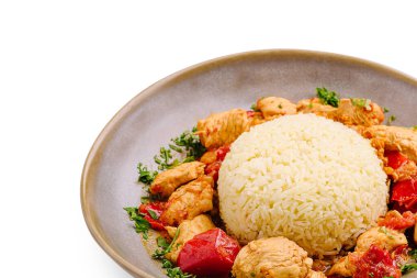 Lezzetli tavuk parçaları renkli sebzelerle pişirilir ve bir yığın kabarık pirinç ile servis edilir. Yemek zarif bir şekilde şık bir kasede ayarlanmış, görsel olarak çekici kılıyor..