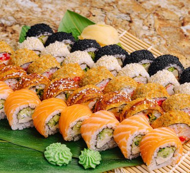 Canlı bir suşi çeşidi bambu bir tepside çeşitli renk ve dokuları sergiliyor. Wasabi ve zencefil lezzet arttırmak için suşiye eşlik ederler..